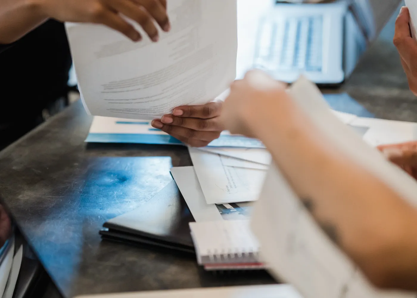 Manos intercambiando documentación sobre un escritorio de oficina